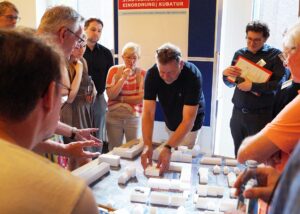 Eine Gruppe von Menschen diskutiert um ein Architekturmodell in einer Präsentation.