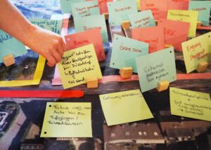 Bunte Notizen auf einem Tisch, einige mit handschriftlichen Notizen, umgeben von Holzständern.